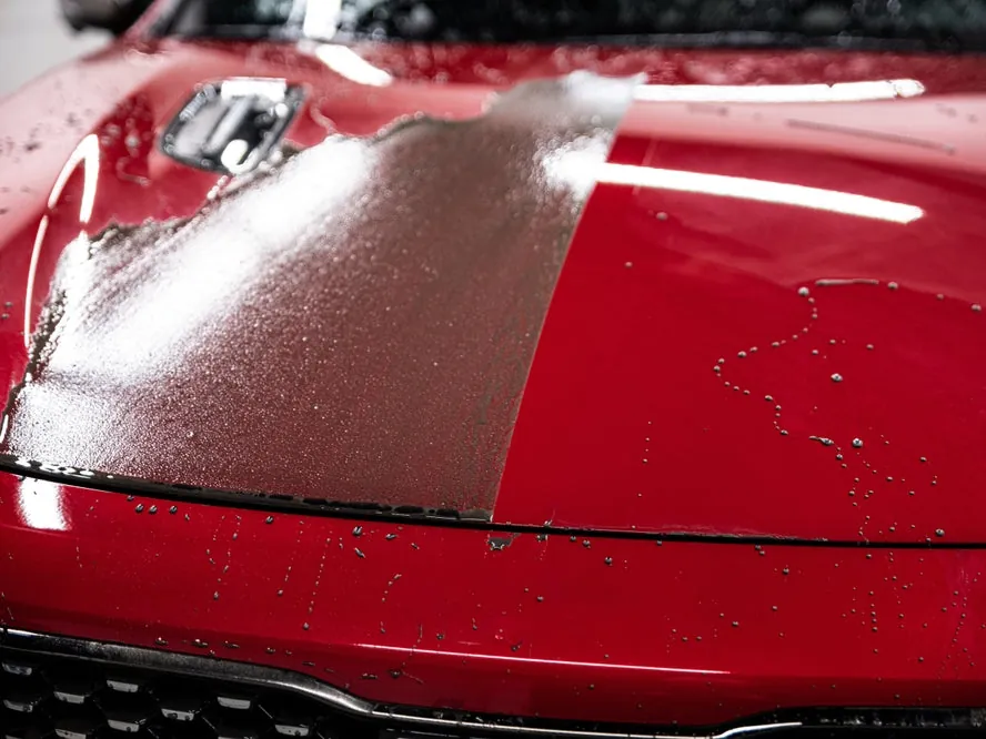 Red bonnet half coated, showing the gloss of Borophene 10H against uncoated paint